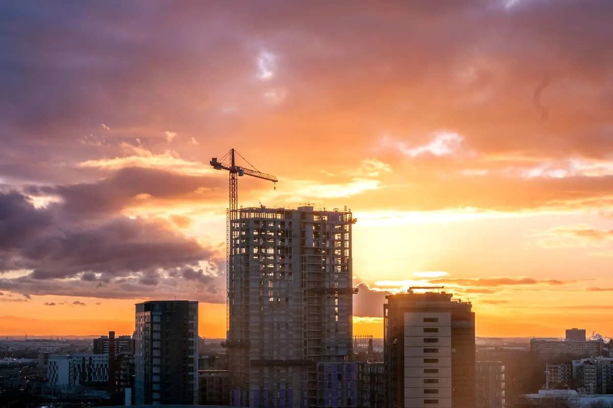 Construction cranes over a UK development at sunset